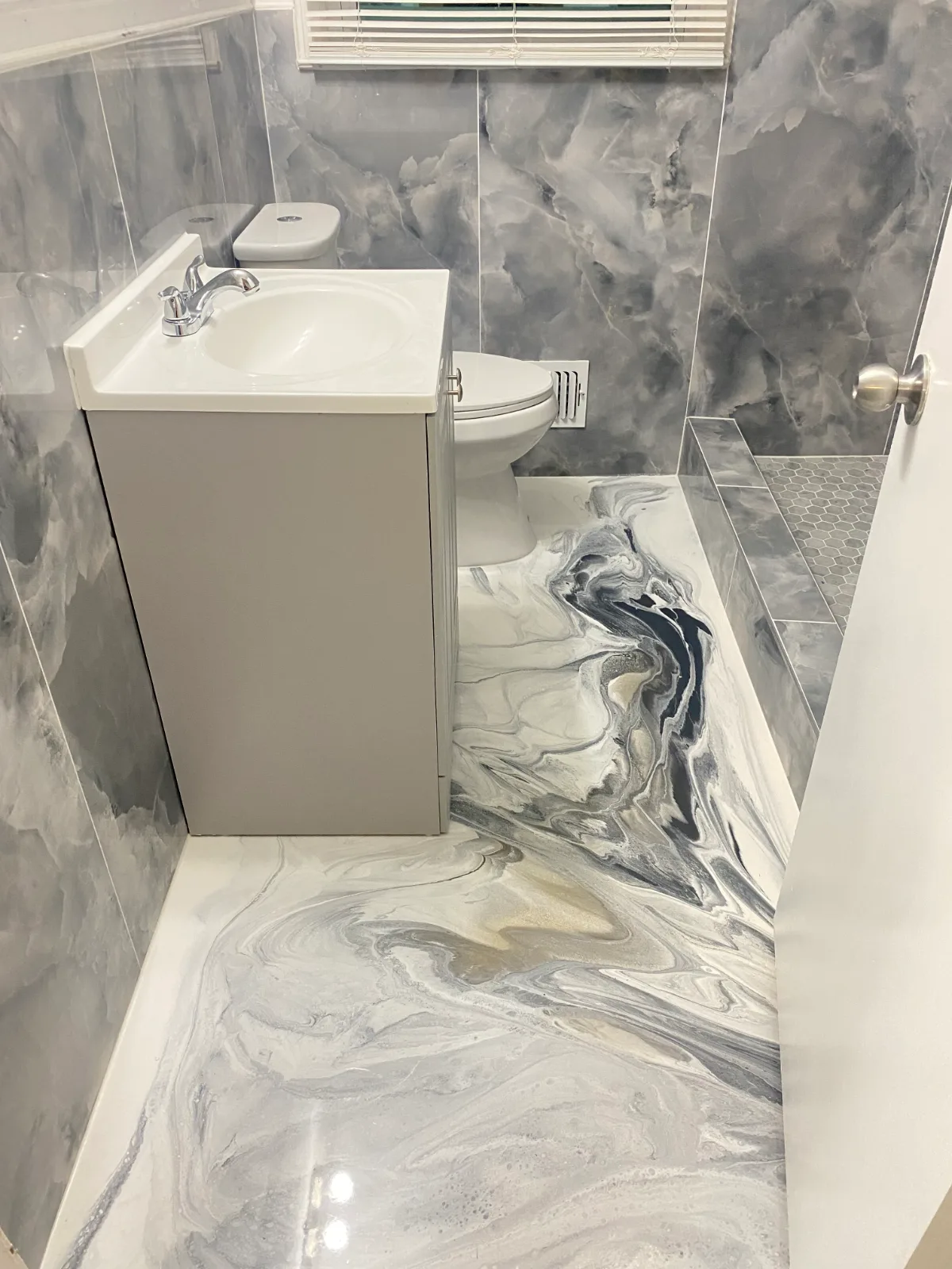 White and grey marble-swirl epoxy feature wall and floor in a bathroom